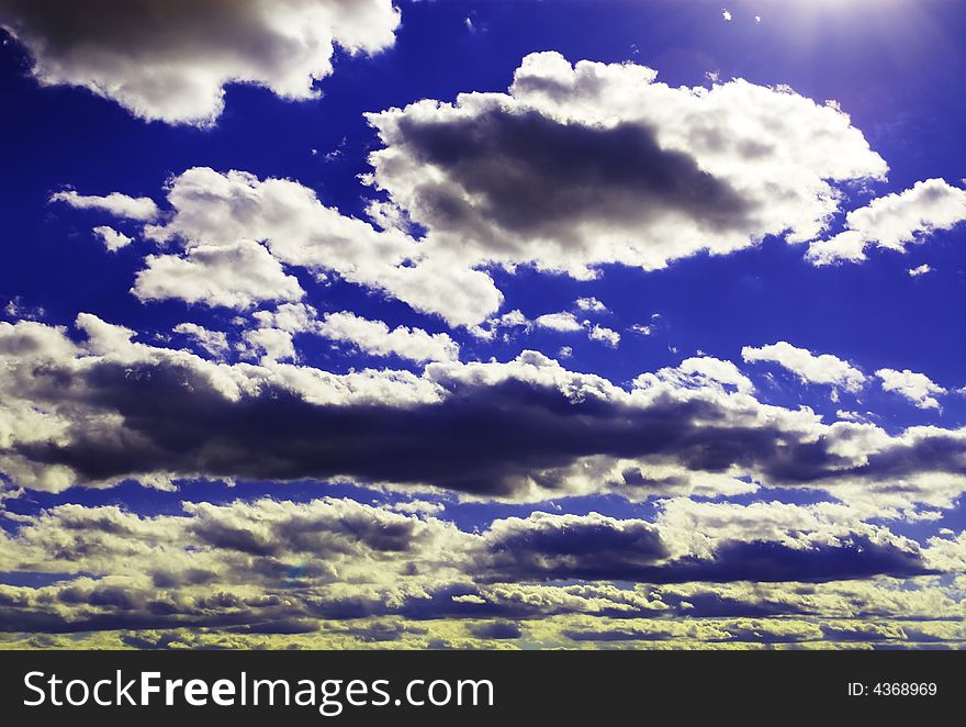 Sunbeams shooting through a blue sky with clouds. Sunbeams shooting through a blue sky with clouds.