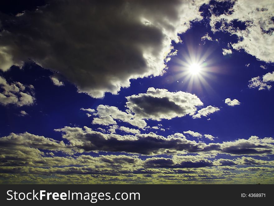 Sunbeams shooting through a blue sky with clouds. Sunbeams shooting through a blue sky with clouds.