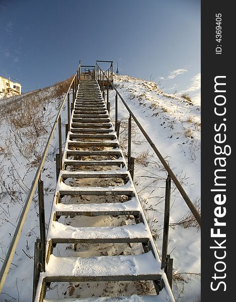 Ladder on a snow mountain on a background of the light-blue sky. Ladder on a snow mountain on a background of the light-blue sky.
