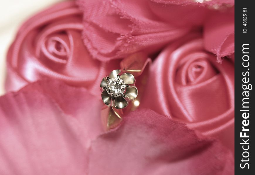 Diamond ring in satin roses. Shallow depth of field, focus on the ring