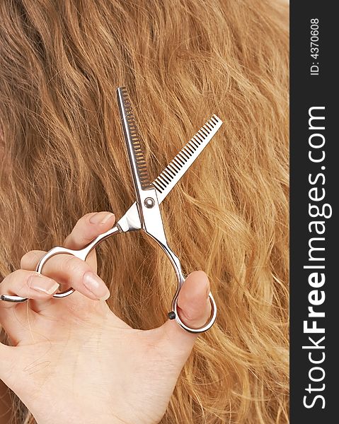 Hairstylist cutting long blond hair with professional scissors