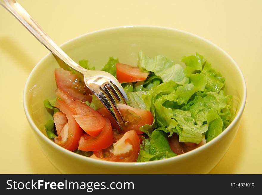 Bowl of fresh salad on yellow background