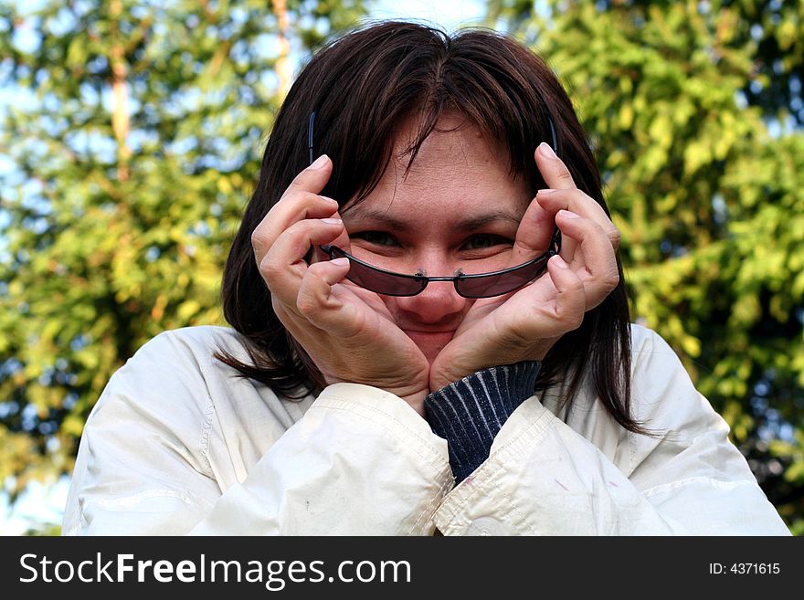 A women smiling holding sunglasses. A women smiling holding sunglasses