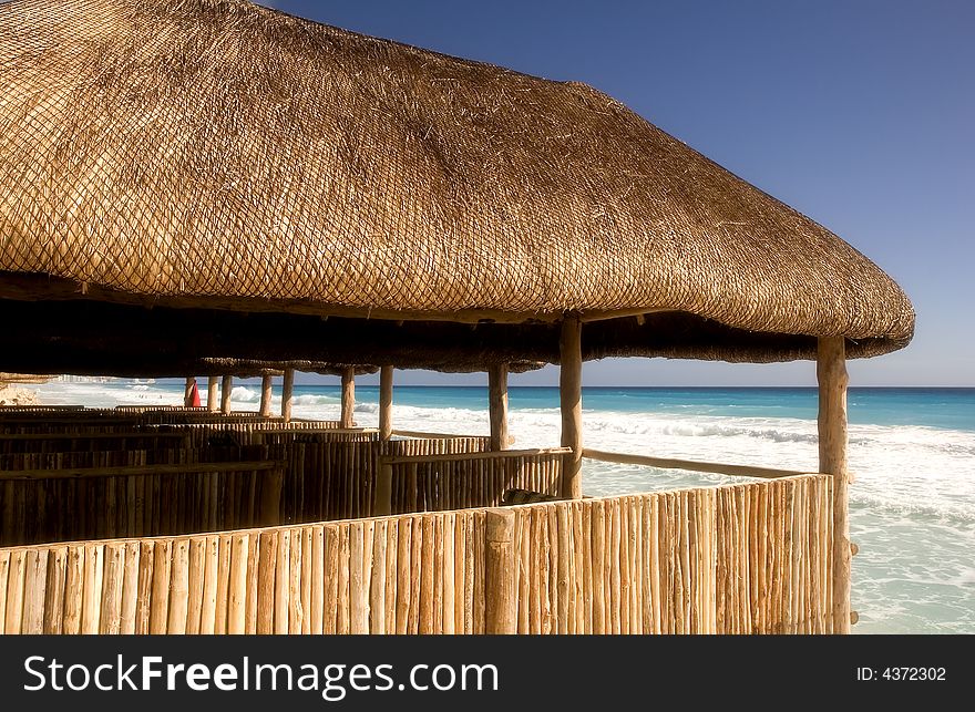 Straw and bamboo cabanas on the beach in front of a resort