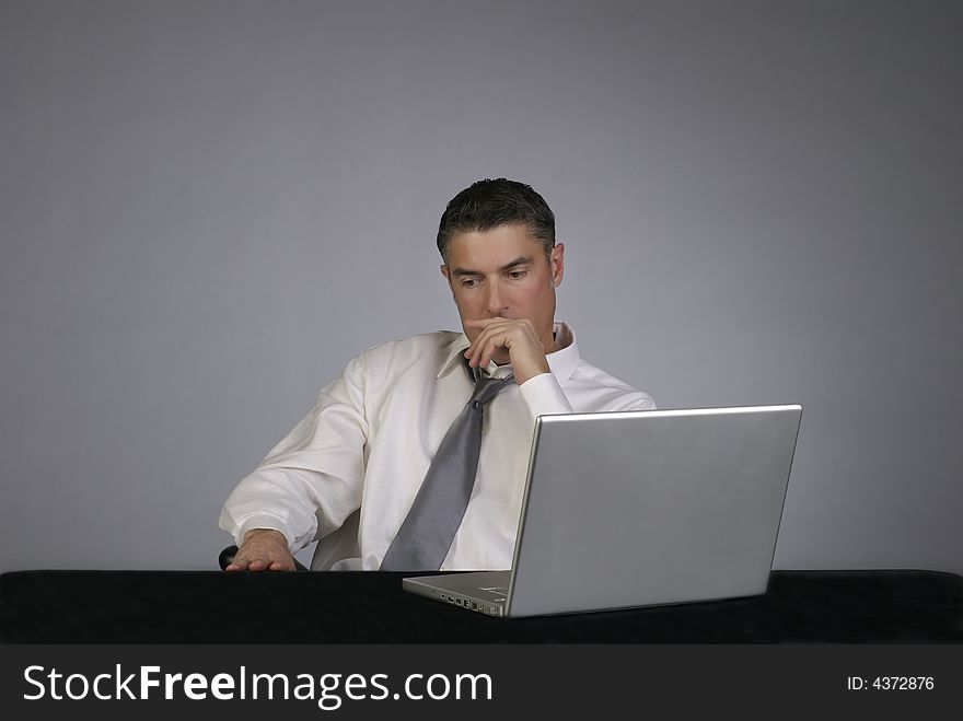 A professional business man in suit and tie sits on office chair looking seriously away from computer. A professional business man in suit and tie sits on office chair looking seriously away from computer.