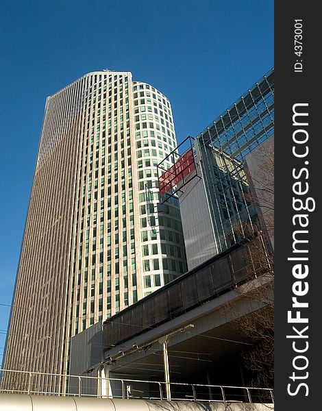 Highrise building against a clear blue sky. The building is the ministry of education in The Netherlands. The lower building in front is the ministry of environment and housing