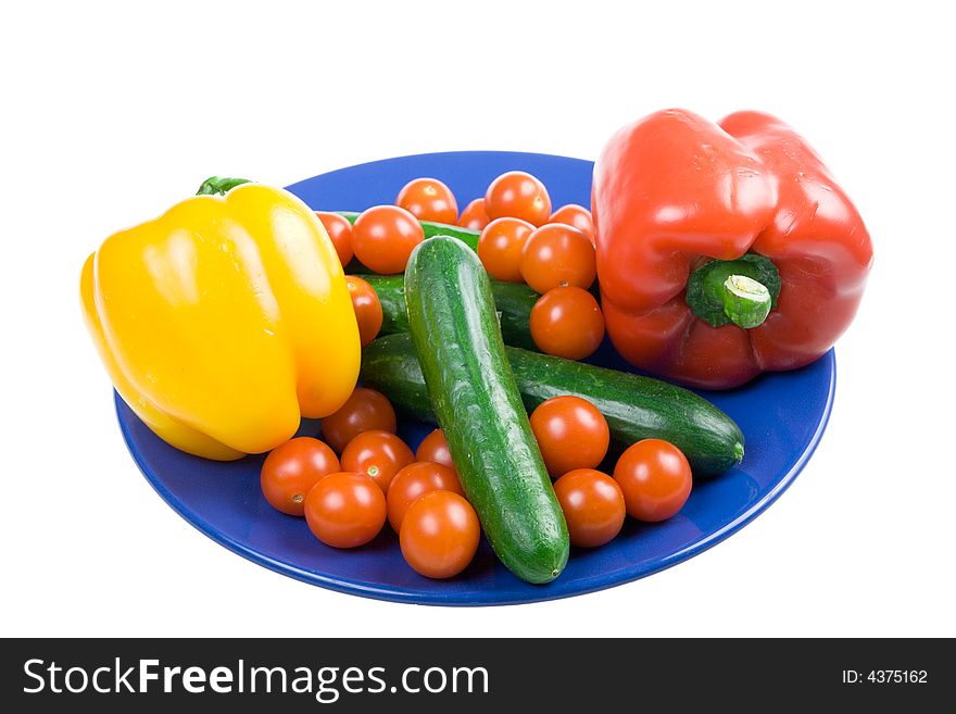 Set of vegetables on a dark blue plate isolated on a white background. Set of vegetables on a dark blue plate isolated on a white background