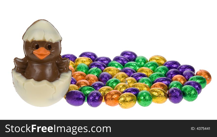 Cute easter chick surrounded by chocolate easter eggs isolated on a white background
