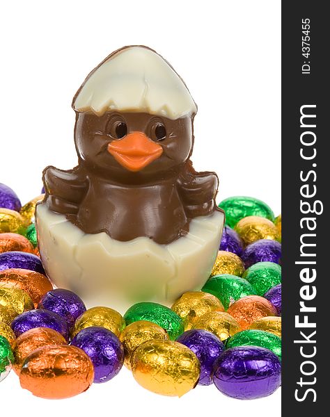 Cute easter chick surrounded by chocolate easter eggs isolated on a white background