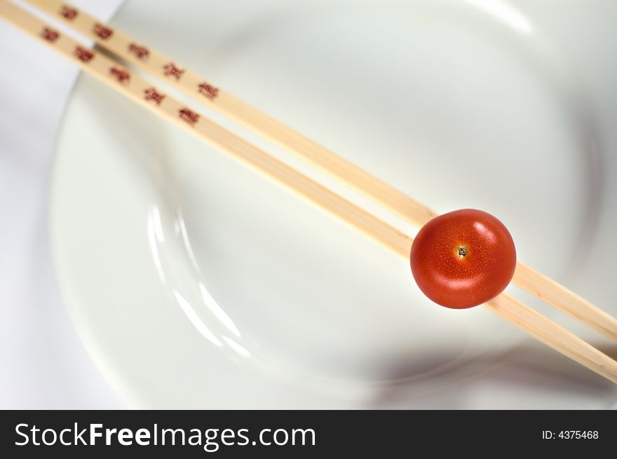 Cherry tomatoe on a white plate with chopsticks. Cherry tomatoe on a white plate with chopsticks
