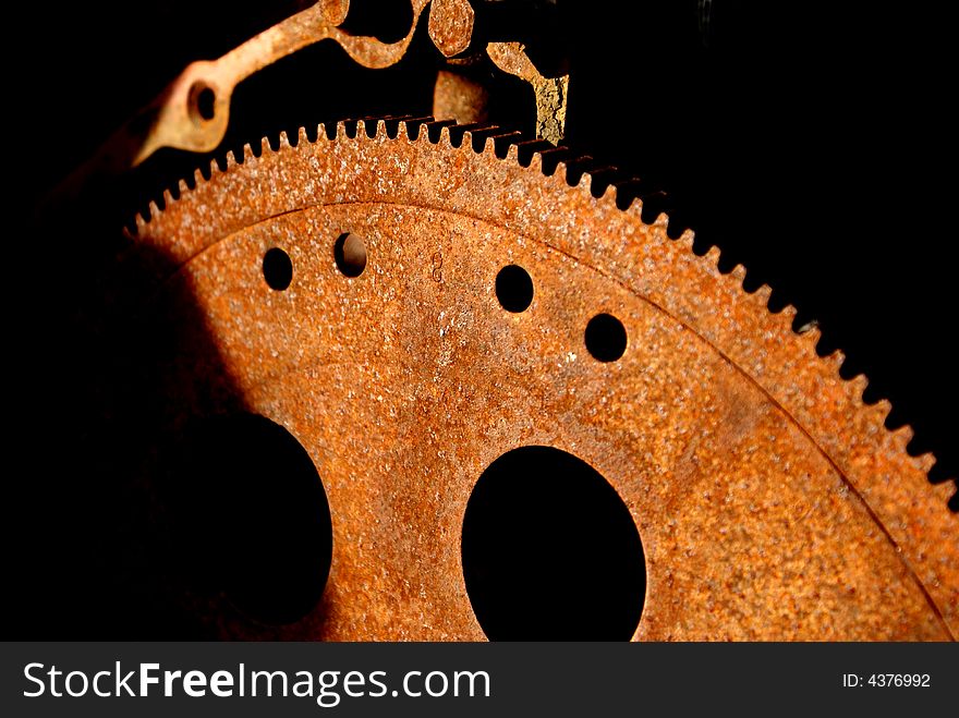 Soft focus image of rusty gears in junk yard against black backdrop with circles and various shapes and forms