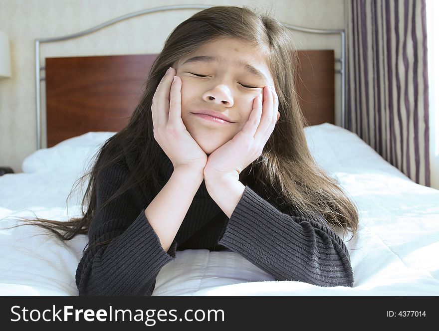 Six year old girl chin on hands thinking while lying down on bed. Six year old girl chin on hands thinking while lying down on bed