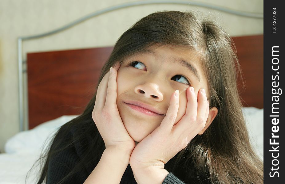 Six year old girl chin on hands thinking while lying down on bed. Six year old girl chin on hands thinking while lying down on bed