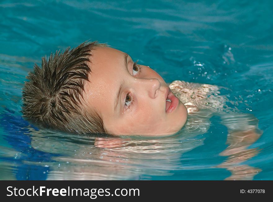 A young boy swimming in a pool. A young boy swimming in a pool