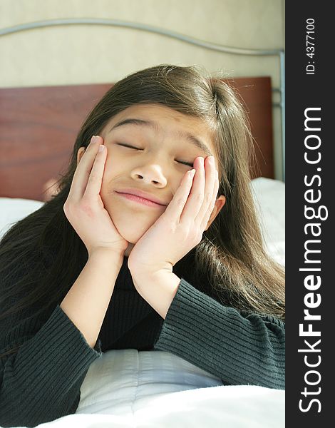 Six year old girl chin on hands enjoying peace and quiet while lying down on bed. Six year old girl chin on hands enjoying peace and quiet while lying down on bed
