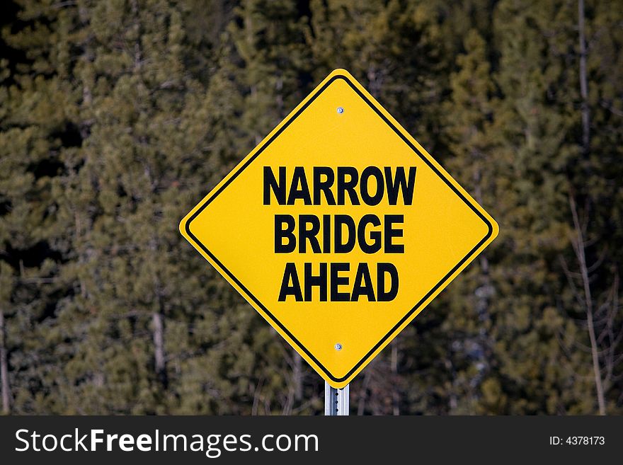 A yellow sign with narrow bridge ahead in black lettering