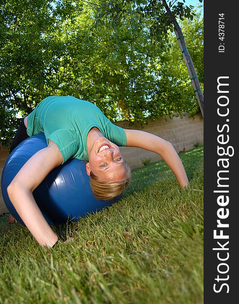 Attractive young woman working out in her backyard with a ball. Attractive young woman working out in her backyard with a ball