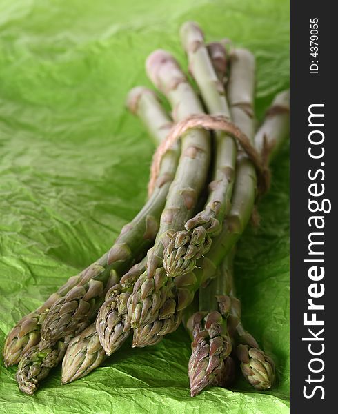 Bundle of asparagus tied together by rope on green background