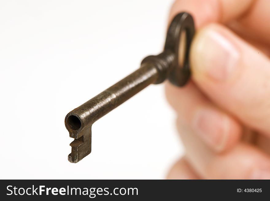 A hand holding an old key. Looks like it's about to open something. Isolated on white background. focus on the front of the key. A hand holding an old key. Looks like it's about to open something. Isolated on white background. focus on the front of the key