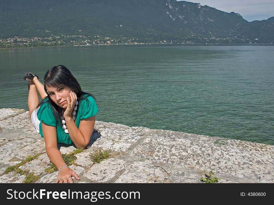 Woman lengthened at the edge of a lake