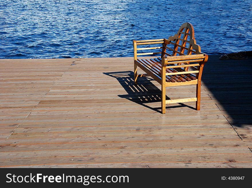 Bench on a deck next to the inlet of a harbor. Bench on a deck next to the inlet of a harbor