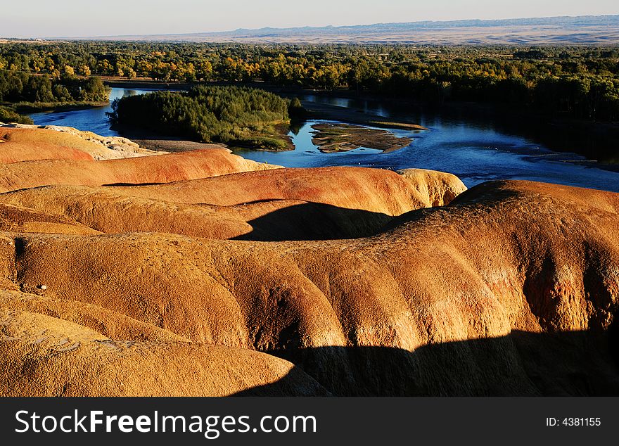 Multicoloured beach located in xinjiang,China.Under sunset, the stone showed a lot of colors. Blue water and trees aside