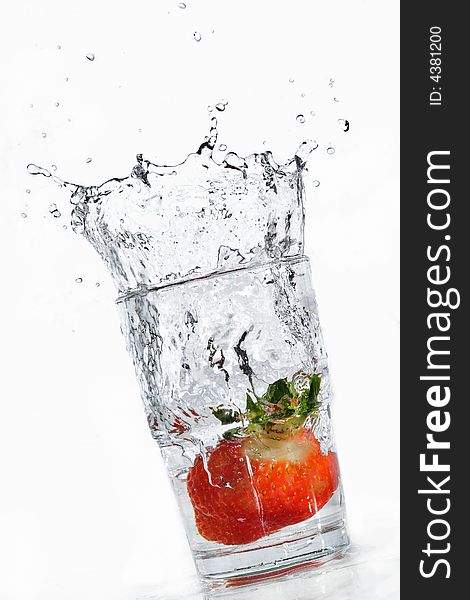 A strawberry making its way into a glass full of water. A strawberry making its way into a glass full of water