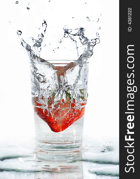 A strawberry making its splash into a glass of water. The water splash taking the shape of the strawberry from the way it enters the water. A strawberry making its splash into a glass of water. The water splash taking the shape of the strawberry from the way it enters the water.