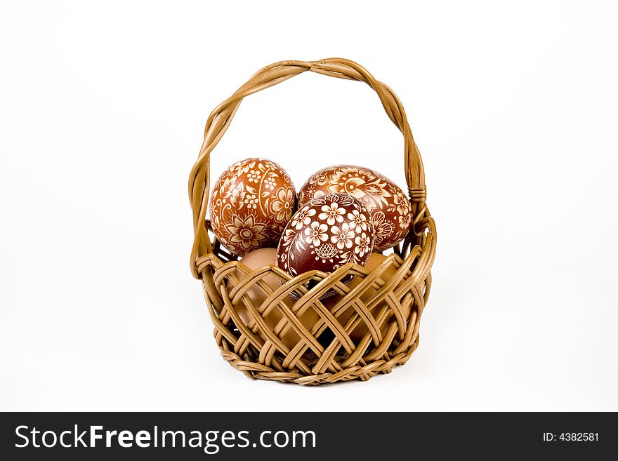 Wicker basket full of easter eggs on white background