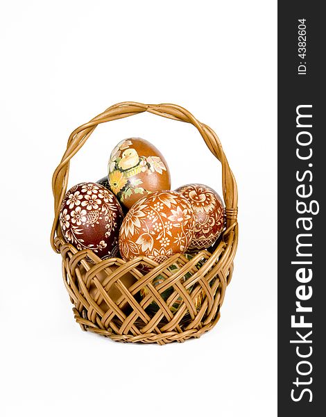Wicker basket full of easter eggs on white background