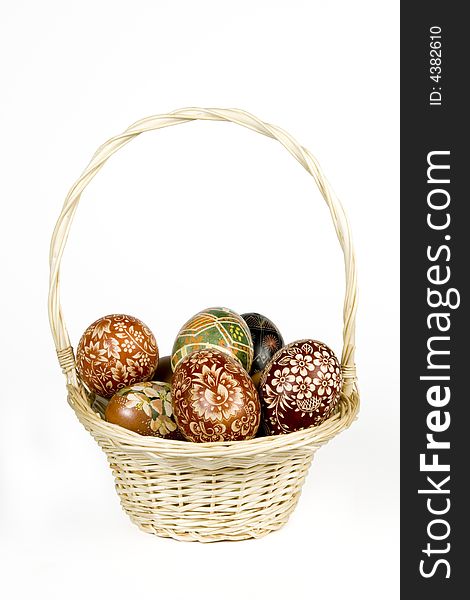 Wicker basket full of easter eggs on white background