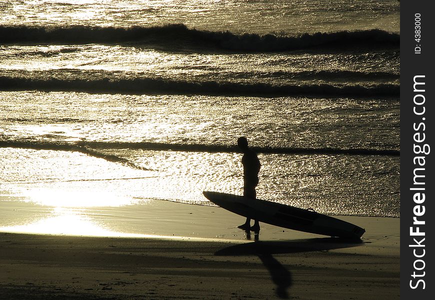 Paddle skier at sunset beside waves at beach. Paddle skier at sunset beside waves at beach