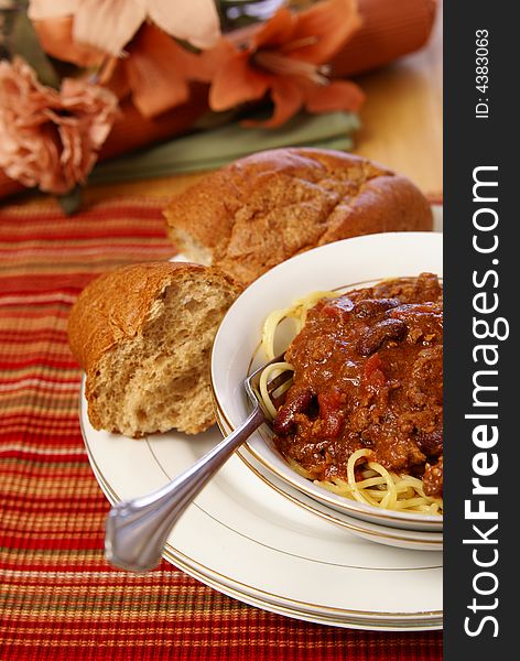 Western style meat and bean chili served on top of spaghetti with a side of rustic wheat bread. Western style meat and bean chili served on top of spaghetti with a side of rustic wheat bread.