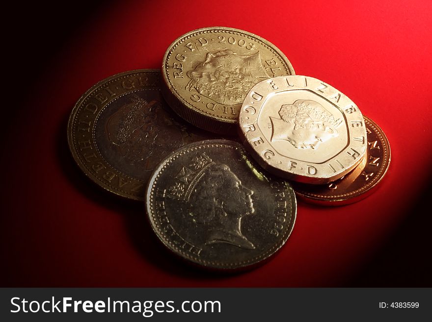 British currency coins on red background with shadows. British currency coins on red background with shadows