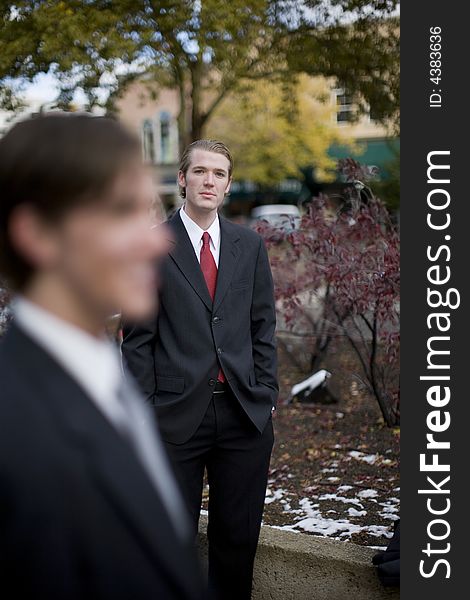 Two businessmen standing next to each other one looking away the other looking at camera. Two businessmen standing next to each other one looking away the other looking at camera