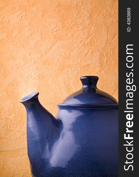 Blue ceramic teapot in front of wall.