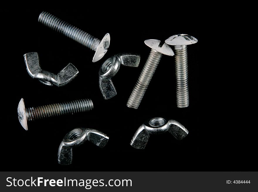 A group of wing nuts and bolts, isolated on a black background.
