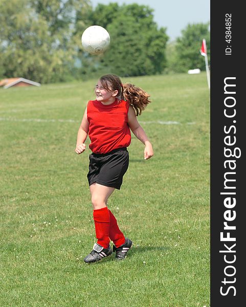 Teen Youth Soccer Player playing ball off head during soccer game. Teen Youth Soccer Player playing ball off head during soccer game.