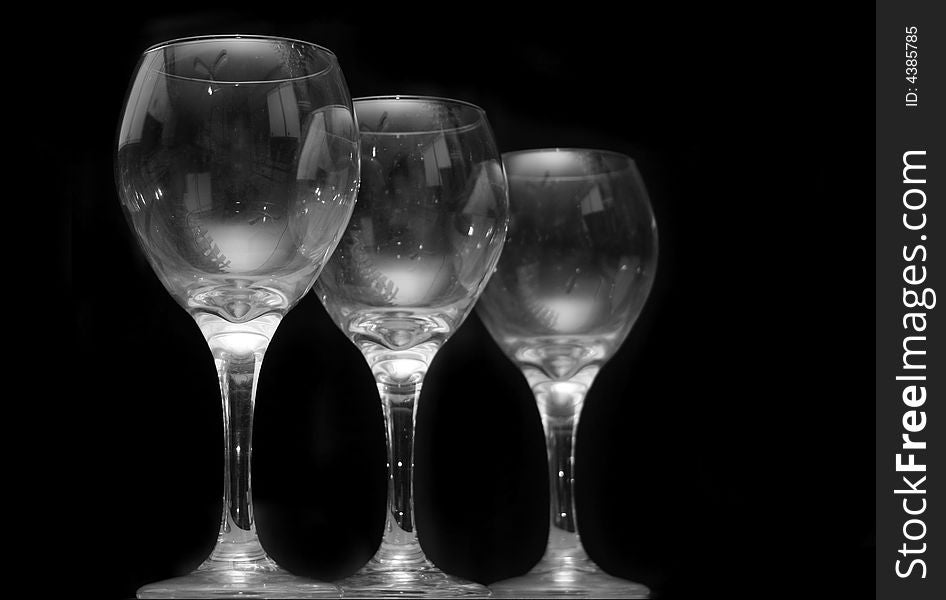 Three wineglasses with light reflections and a black background reflections. Three wineglasses with light reflections and a black background reflections