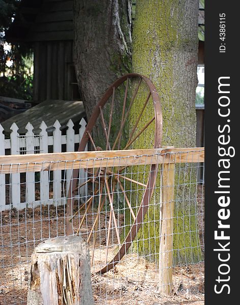 Rusty waggon wheel against a country fence. Rusty waggon wheel against a country fence