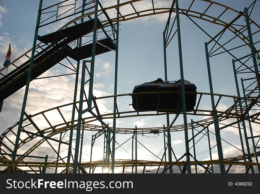 Carnival ride with metal rods and struts against blue sky and clouds. Carnival ride with metal rods and struts against blue sky and clouds