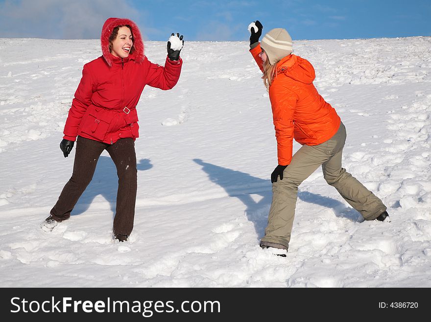 Two beautiful young women play to snowballs. Two beautiful young women play to snowballs