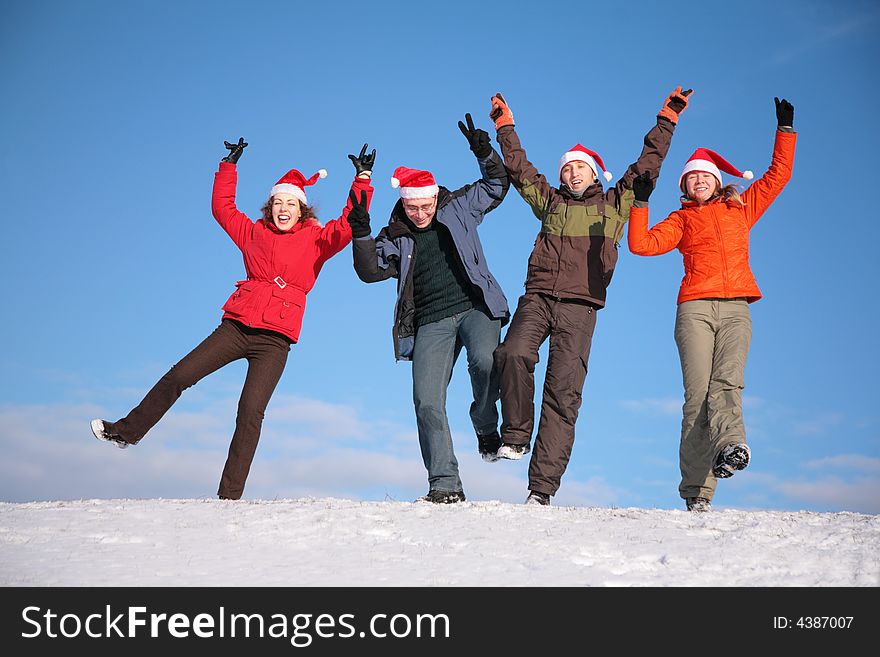 Four friends jump on top of snow hill in santa claus hats. Four friends jump on top of snow hill in santa claus hats