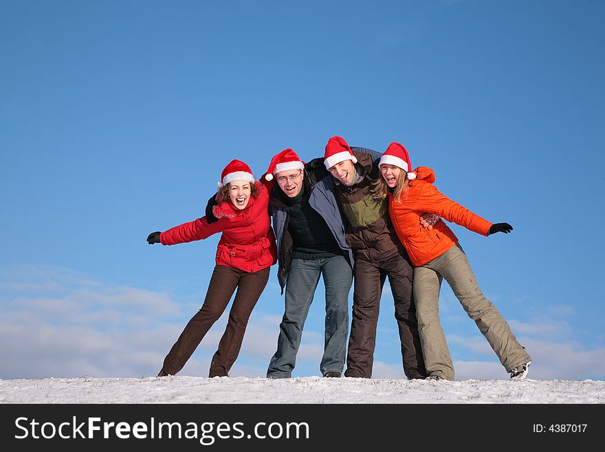 Four friends embracing on top of snow hill in santa claus hats. Four friends embracing on top of snow hill in santa claus hats