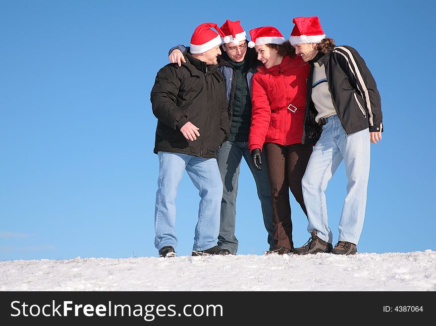 Four friends talk on snow in santa claus hats. Four friends talk on snow in santa claus hats