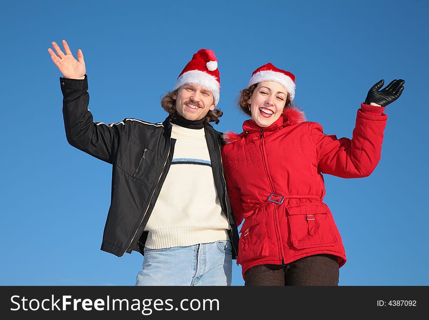 Couple against blue sky background in winter in santa claus hats
