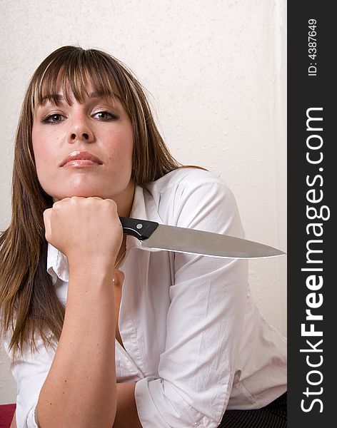 Business woman holding a knife with her knuckle to her chin ready for action. Business woman holding a knife with her knuckle to her chin ready for action.