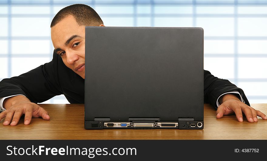 Business man playing hide and seek behind his laptop in his office because of boredom. Business man playing hide and seek behind his laptop in his office because of boredom