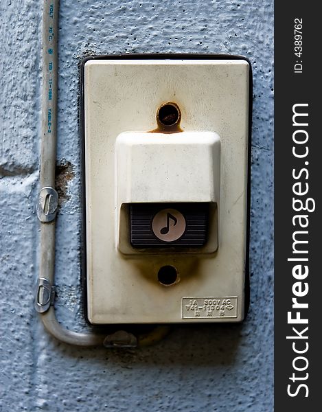 A dirty looking door bell buzzer on a wall