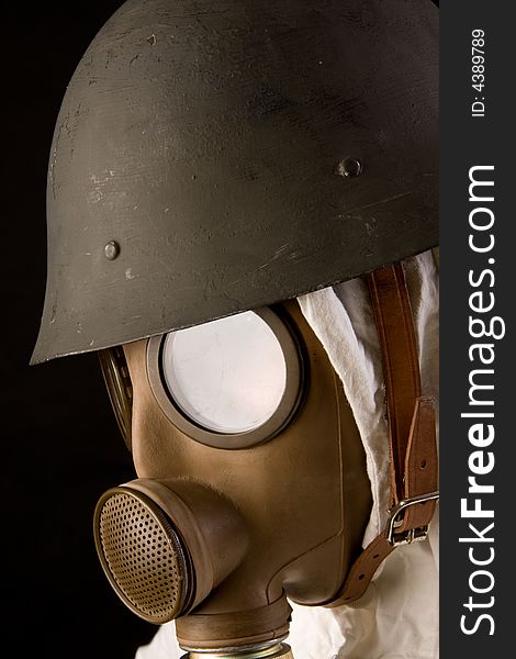 Military person in gas mask and helmet on black background